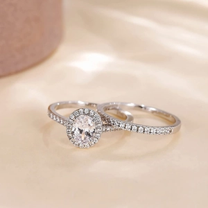 Nahaufnahme des ovalen Verlobungsring-Sets mit Pavé-Diamanten auf Champagner-Seide