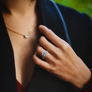 Detail eines silbernen Ringes und einer Goldkette mit Blumenanhänger am Anzug