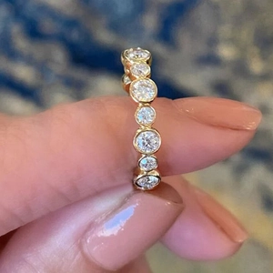 Close-up of gold plated eternity ring with round bezel-set cubic zirconia on finger
