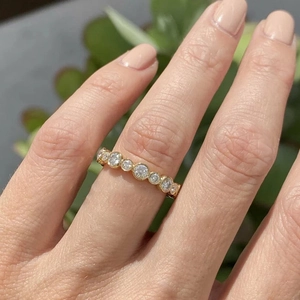 Close-up of a gold bezel-set cubic zirconia eternity band on a model's finger