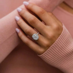 Bague de fiançailles élégante avec coupe coussin et halo sur la main avec pull rose