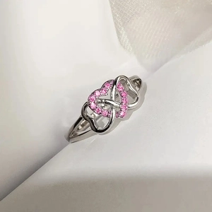 Close-up of interlocking heart ring with pink pavé zircons and polished silver finish