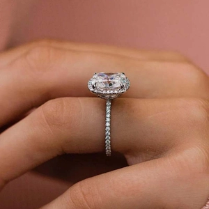 Bague de fiançailles luxueuse avec halo coussin et anneau pavé sur un doigt