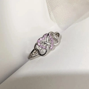 Detailed view of silver heart ring featuring pink cubic zirconia pavé on satin background