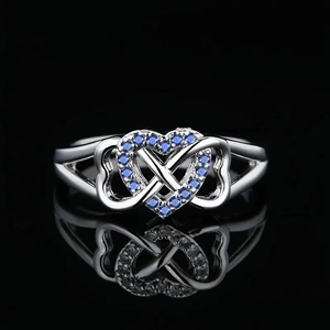 Detail of silver heart infinity ring with blue cubic zirconia on black background