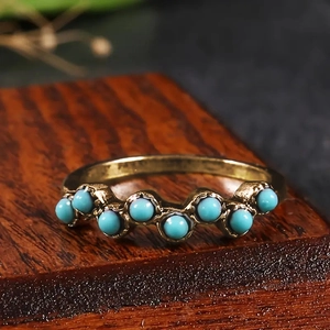 Vue macro d'une bague rétro dorée avec sept perles turquoise sur un socle en bois