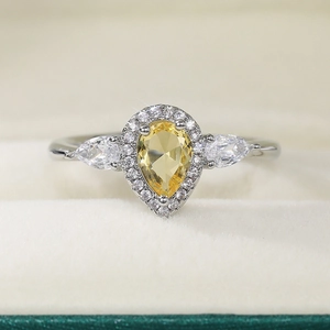 Macro dettaglio di anello in zircone giallo a goccia con diamanti halo laterali