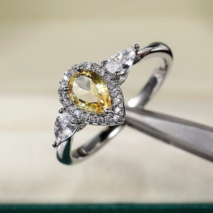 Dettaglio macro dell'anello con zircone giallo a goccia e incastonatura halo con pinzette