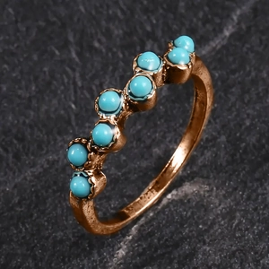 Vue détaillée d'une bague bohème en or rose avec perles turquoise sur fond de pierre