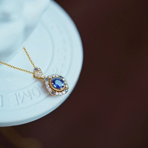 Luxury oval blue sapphire pendant necklace with gold chain and sparkling crystal halo