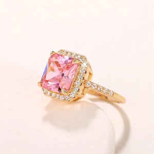 Nahaufnahme eines pinkfarbenen quadratischen Edelsteinrings mit Diamant-Halo in Gold