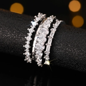 Detailed view of a three-piece silver ring set with sparkling zircons on a black display stand