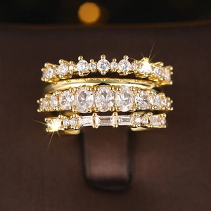 Close-up of four gold-plated geometric rings with assorted crystal stone settings