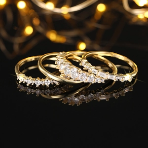 Macro shot of gold geometric ring set with sparkling zircon on a black reflective surface