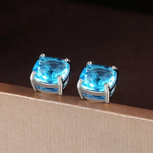 Nahaufnahme der blauem Zirkon Ohrstecker mit Kissen-Schliff und silberner Vier-Krallen-Fassung