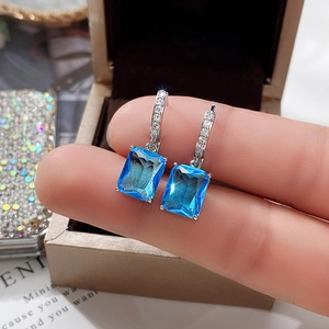 Macro shot of silver drop earrings featuring large rectangular blue cubic zirconia stones