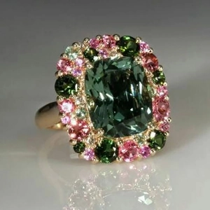 Detalle de anillo esmeralda corte cojín con halo de piedras rosas y verdes finas