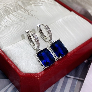 Detailed macro of silver earrings with dark blue rectangular zircon and pavé settings