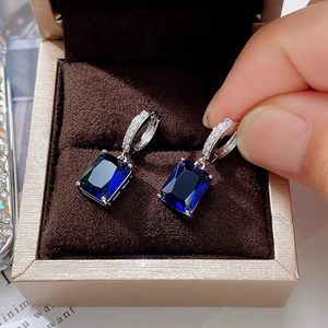 Detail of blue rectangular zircon earrings in a premium jewelry box held by hand