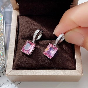Macro shot of silver drop earrings with emerald-cut pink zircon and pavé diamond details