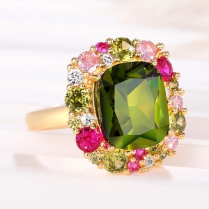 Detalle macro de anillo vintage dorado con piedra esmeralda y halo de gemas coloridas