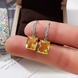 Close-up of rectangular yellow zircon earrings with micro-paved silver metal hooks
