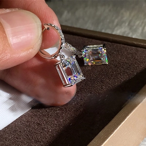 Macro view of emerald-cut clear zircon earrings with micro-pave diamonds in silver finish