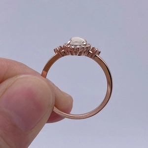 Macro detail of rose gold halo ring featuring an oval cabochon stone and tiny zircon accents