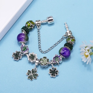 Silver charm bracelet with green four-leaf clover pendant and purple glass beads