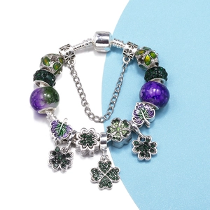 Silver snake chain bracelet featuring green and purple four-leaf clover charms and glass beads