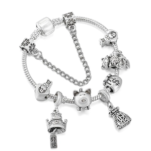 Bracelet serpent argenté avec breloques chat de la fortune et sac d'argent sur fond blanc