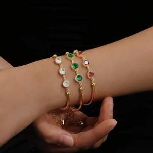Detail of gold bamboo chain bracelets with colorful round-cut zircon stones on wrist