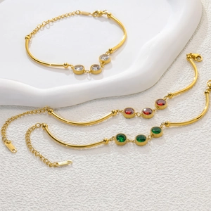 Detailed view of gold bamboo chain bracelets with red, green and clear crystals