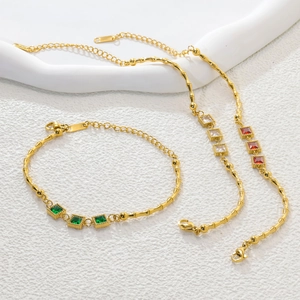Detail of gold bamboo-link chains with square emerald, white and ruby colored zircons