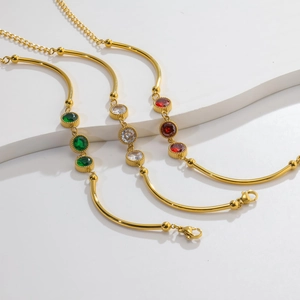 Detail of gold bamboo bracelets with three round gemstones in emerald, clear and red stones