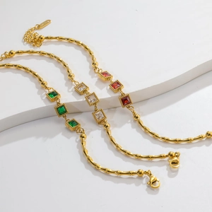 Detail of gold bamboo link bracelets with square emerald, ruby and white crystals