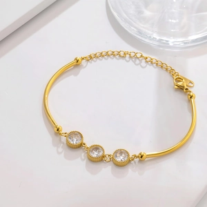Close-up of a gold bracelet with three round cubic zirconia stones and a lobster clasp