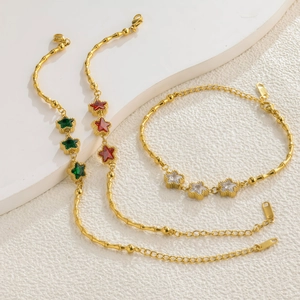 Three gold bamboo chain bracelets with red green and white star-shaped gemstone charms