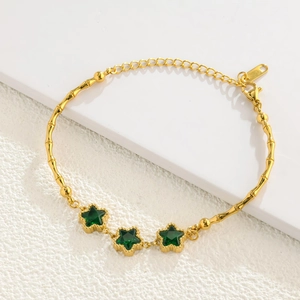 Detail of gold bamboo link bracelet featuring three star-shaped emerald green crystals