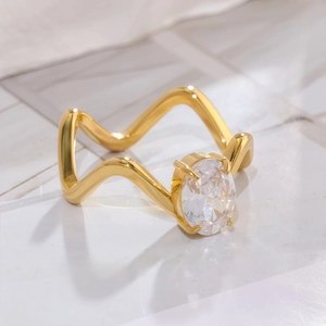 Gros plan sur bague dorée ondulée sertie d'une grande pierre ovale avec griffes de fixation