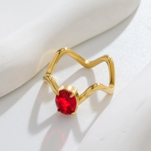 Détail macro d'une bague dorée ondulée ornée d'une pierre précieuse rouge ovale