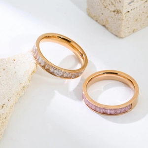 Macro view of rose gold titanium rings with inlaid purple and clear zircons on stone