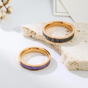 Detailed shot of gold titanium rings with black and purple zircons on a white stone base