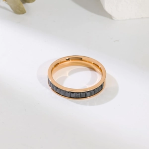 Detail of rose gold ring with channel-set black rectangular stones on white stone