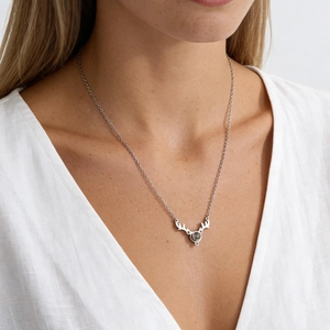 Close-up of silver elk antler pendant with black stone on woman neck necklace