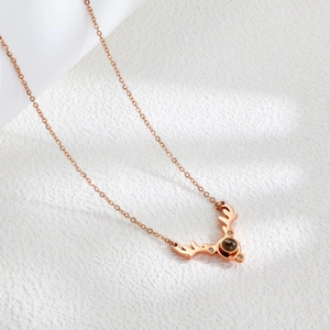 Close-up of rose gold antler pendant with a dark projection stone and zircon inlay