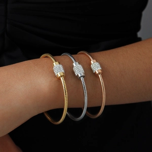 Close-up of tricolor snake bone bracelets in gold, silver, and rose gold with pavé crystals