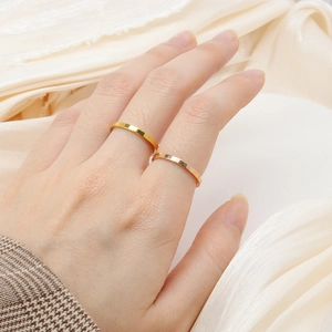 Detail of rose gold and gold faceted rings worn on hand against silk background