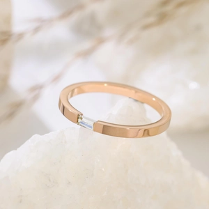 Makroaufnahme von roségoldenem Ring mit Baguette-Schliff auf weißem Quarzkristall