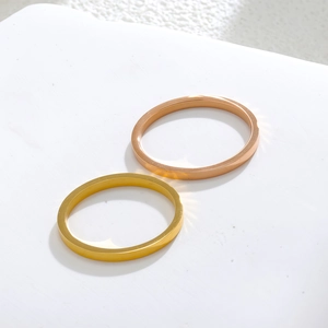 Detailed close-up of polished gold and rose gold minimalist steel bangles on white surface